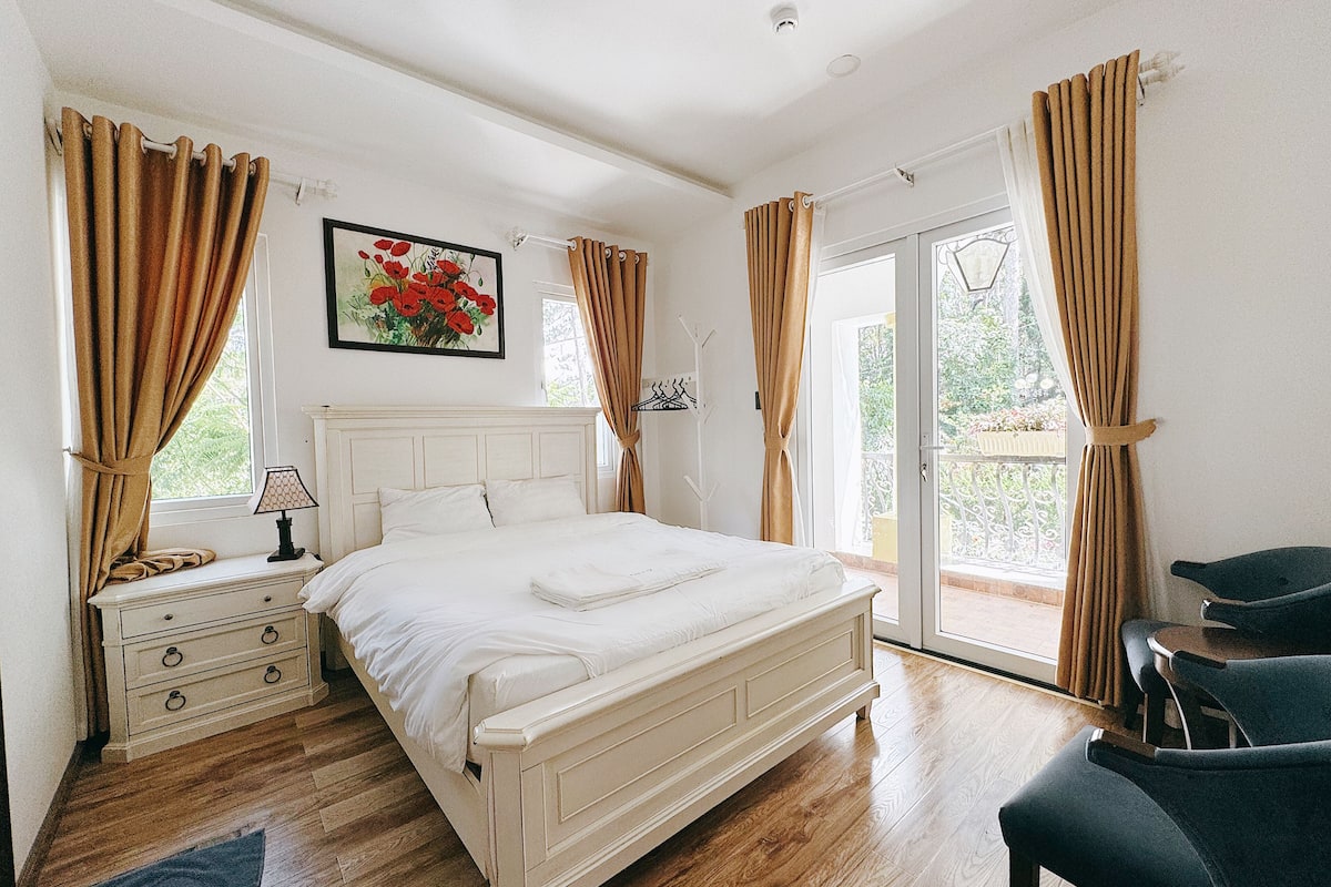 Un dormitorio con una cama, una mesita de noche, una silla y vistas al exterior.