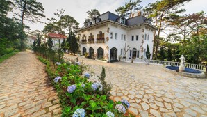 A large, white building with a stone-paved courtyard and a fountain. - TTR Joy Apart Hotel (Xuan Huong - Da Lat)