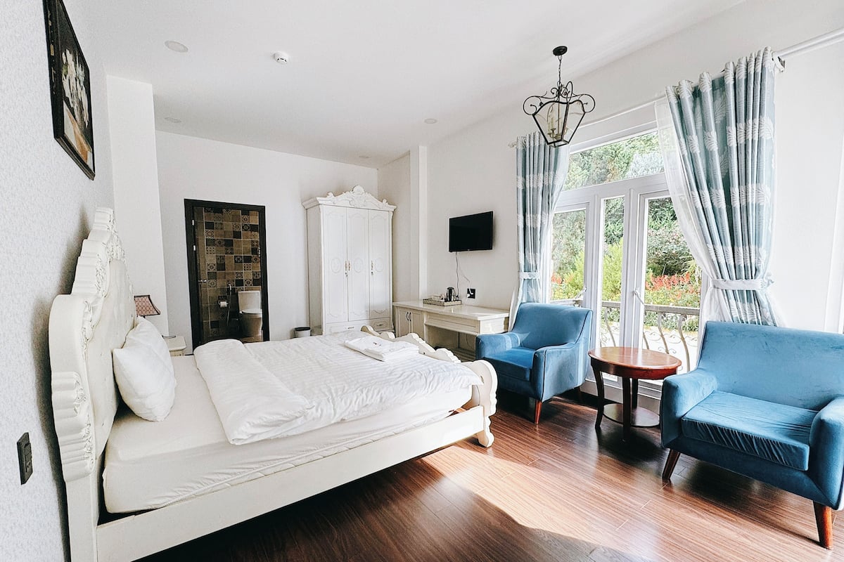 Una habitación de hotel con una cama grande, un escritorio, una silla, un sofá y un televisor.