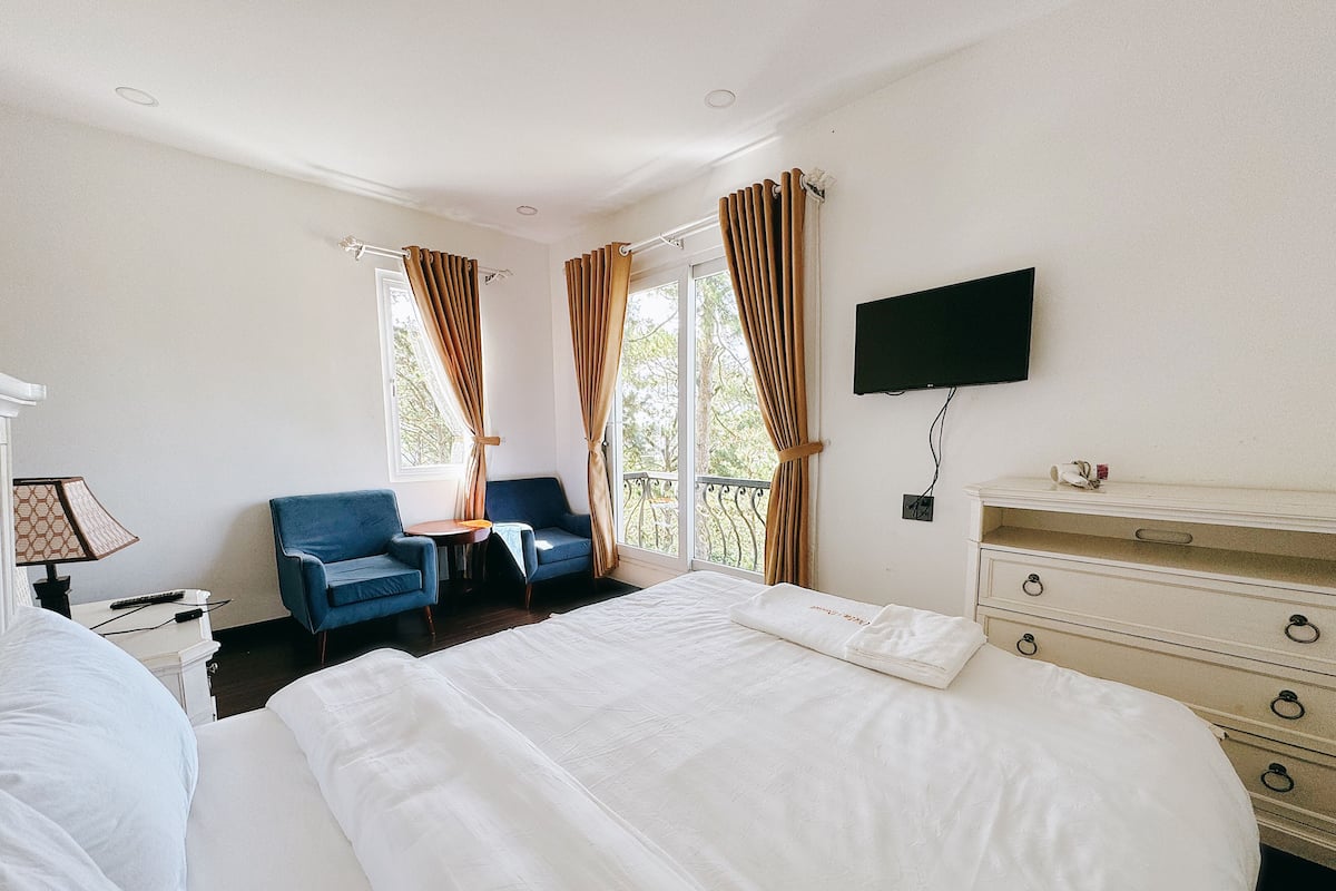 Una habitación de hotel con cama, televisor, cómoda, escritorio y dos sillas.