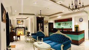 A hotel lobby with a reception desk, two blue sofas, a white coffee table, and a chandelier. - TTR Joy Apart Hotel (Xuan Huong - Da Lat)