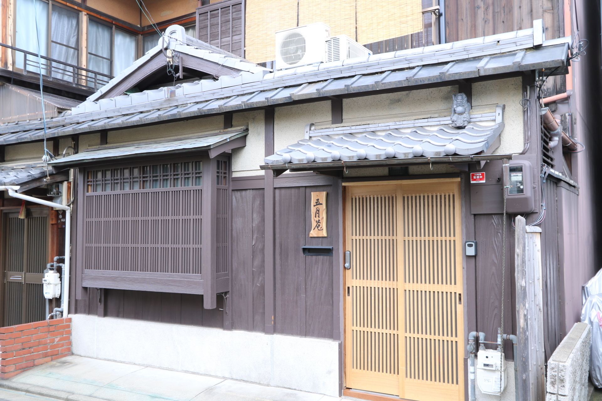 A traditional Japanese building with a wooden exterior, a tiled roof, and a sliding wooden door.
