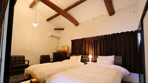 Quarto de hotel com duas camas, teto de madeira, espelho, escrivaninha e uma cadeira.