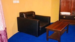 Una habitación con una butaca de cuero negro, una mesa de madera y un amplio armario de madera con espejo.