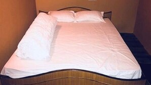 Una cama individual con ropa de cama blanca en una habitación con paredes lisas.
