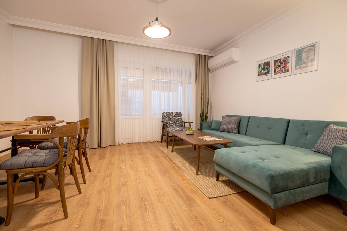 Una sala de estar con una mesa de comedor de madera, sillas, un sofá y una mesita de centro.