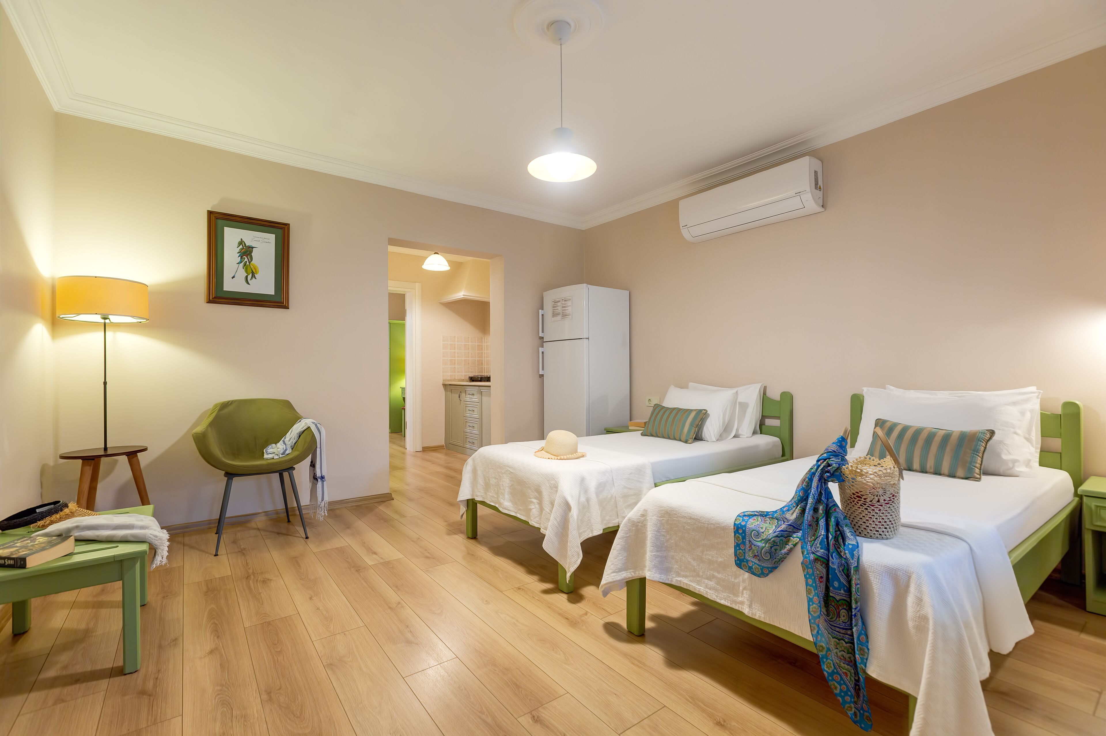 A hotel room with two beds, a desk, a chair, a lamp, and a picture on the wall.