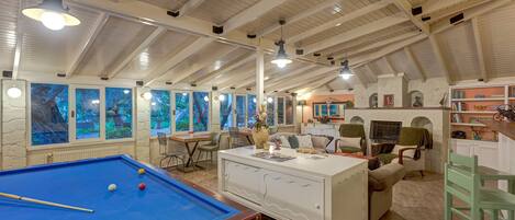 A spacious room with a pool table, comfortable seating, and artwork on the walls.