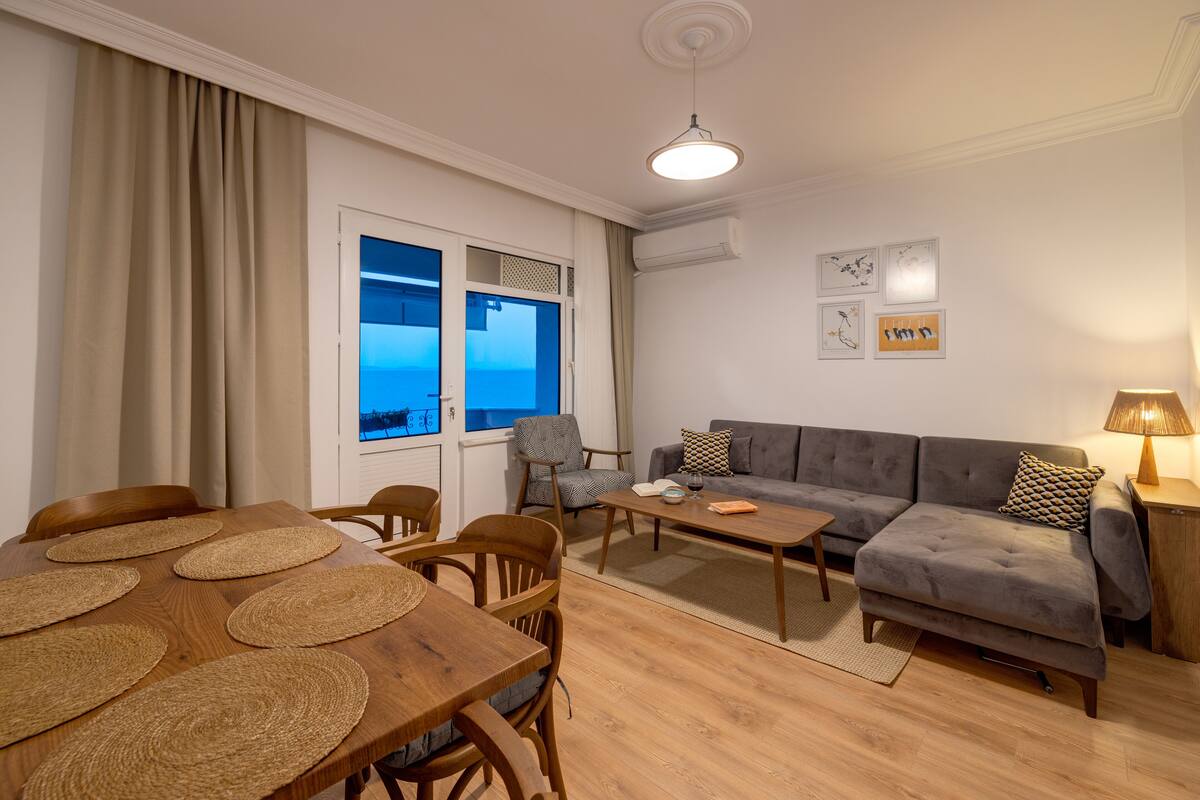Una sala de estar con una mesa de comedor de madera, sillas, un sofá y una mesa auxiliar.