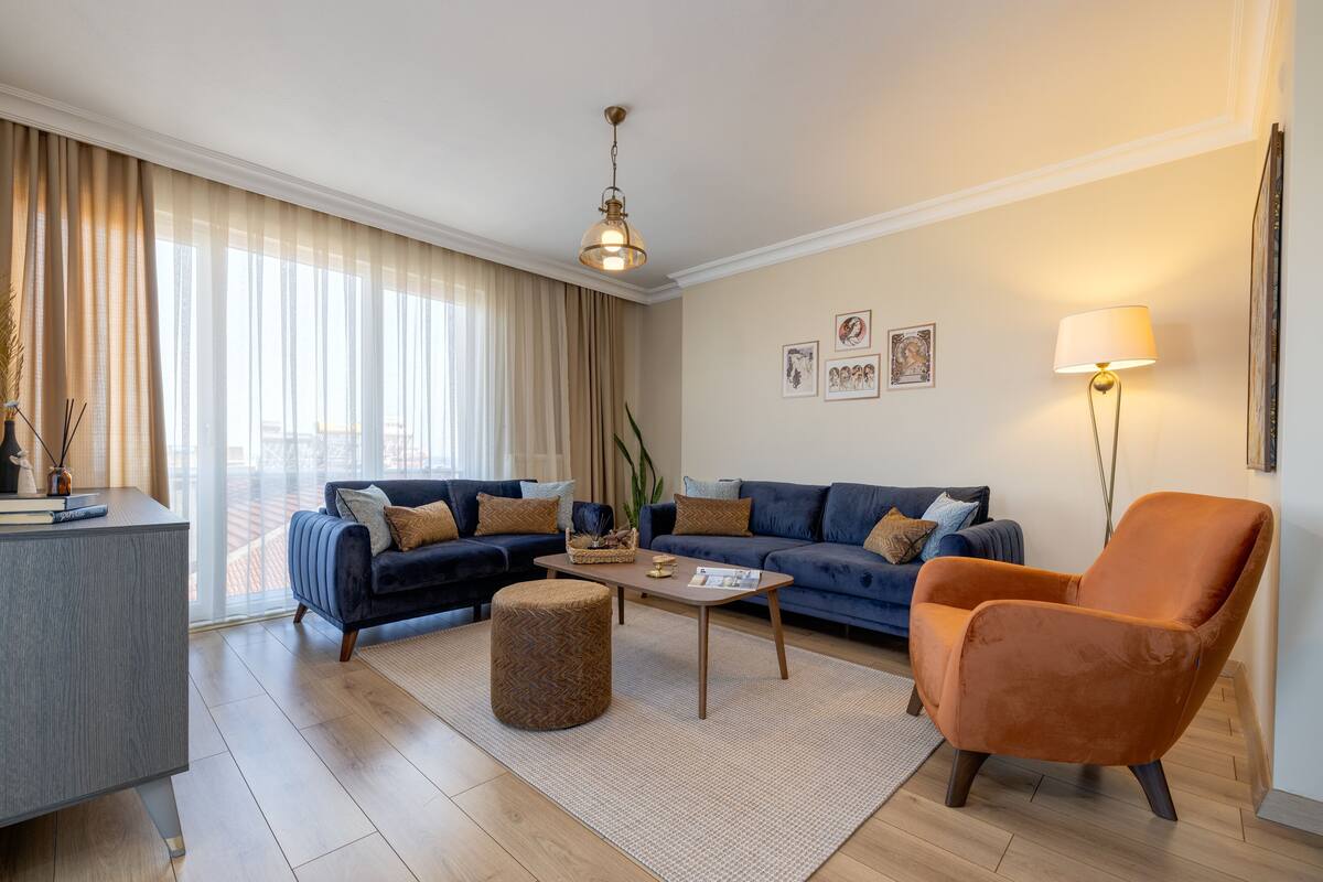 Una sala de estar moderna con sofá, reposapiés, mesa de centro y lámpara.
