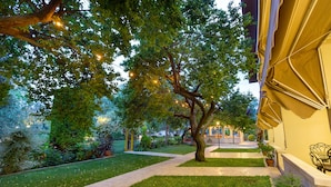 Un jardín bien cuidado con un sendero pavimentado, un árbol grande y mobiliario exterior.