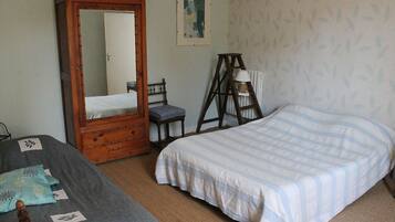 A room with two beds, a wooden wardrobe, a ladder, and a framed picture on the wall.