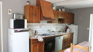 Una cocina compacta con armarios de madera, un microondas, una estufa y un lavavajillas.