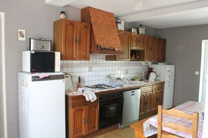 Una cocina compacta con armarios de madera, un microondas, una estufa y un lavavajillas.