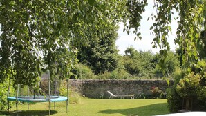 Un patio trasero con un trampolín, una mesa y un muro de piedra.