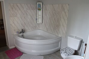 Une salle de bain avec une baignoire sur pieds, des toilettes et un porte-serviettes.