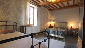 Un dormitorio con dos camas, una ventana con cortinas, una lámpara y techo de madera.