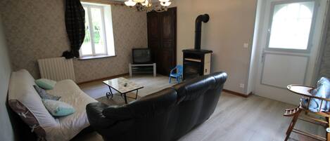 A living room with a sofa, a small table, a TV, and a fireplace.