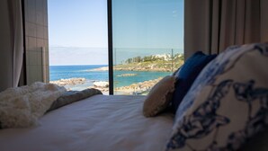 A bedroom with a large window overlooking a beach and ocean. - Villa Lara (Kouklia)