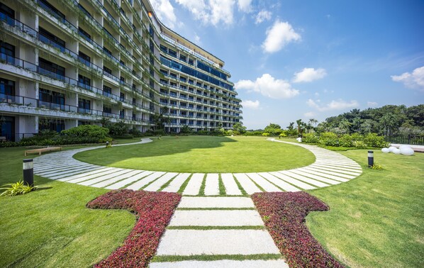 A large hotel with multiple floors, a well-maintained lawn, and a circular garden area.