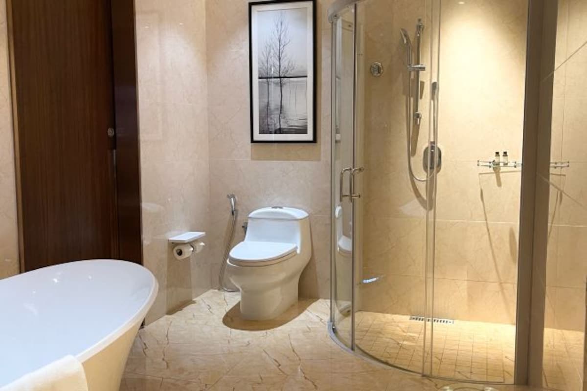 A modern bathroom with a freestanding bathtub, a toilet, and a glass-enclosed shower area.