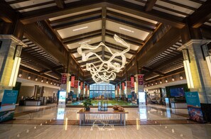 A spacious lobby with a high ceiling, a central seating area, and a large digital display.