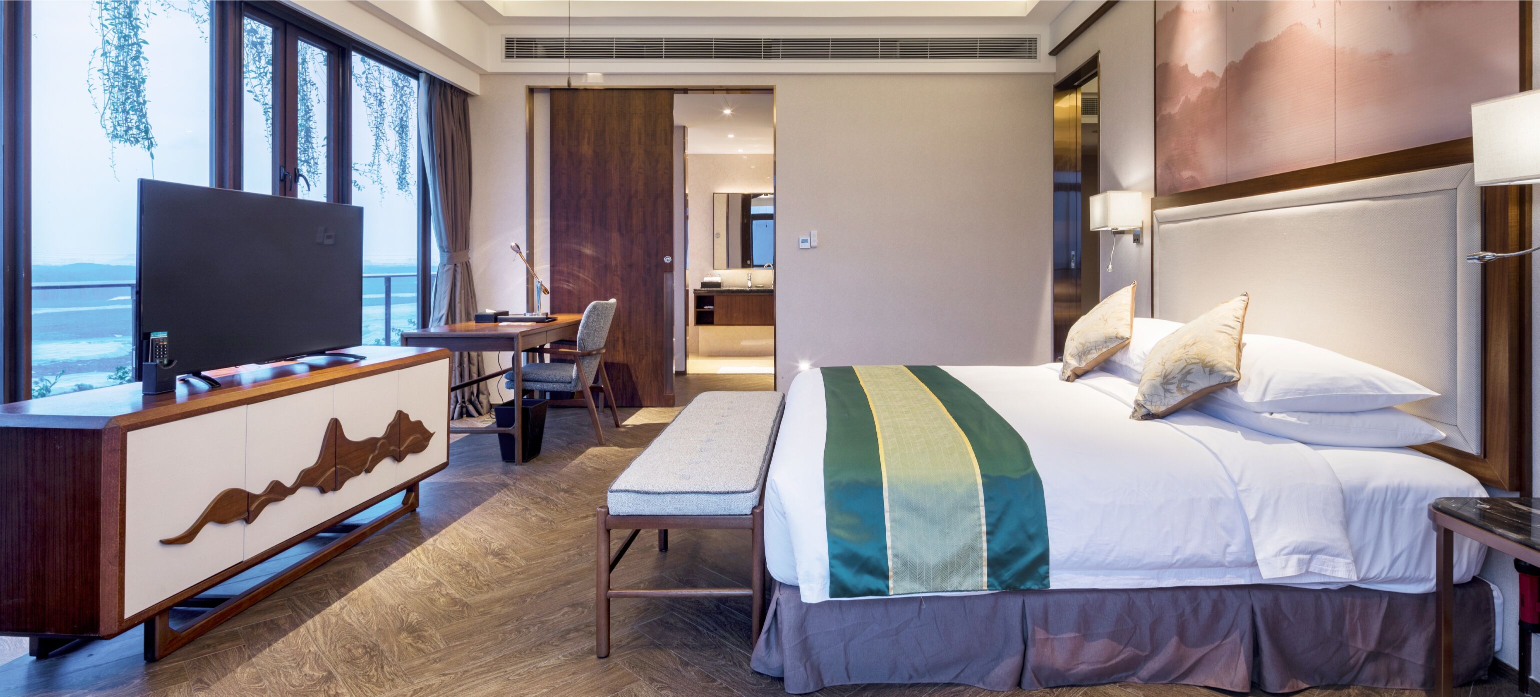 Une chambre d’hôtel avec un lit, un bureau, une chaise, une télévision et une vue sur la mer.