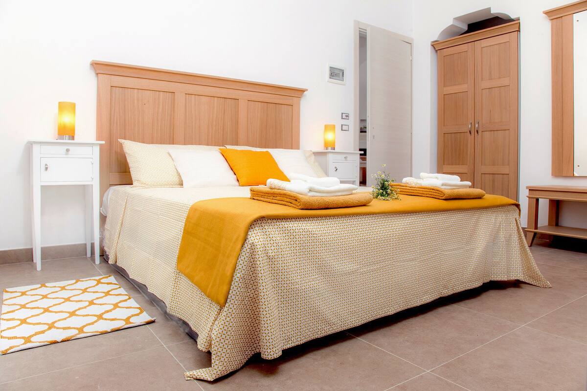 Ein Schlafzimmer mit Bett, Nachttischen, einem Kleiderschrank und einer Badezimmertür.