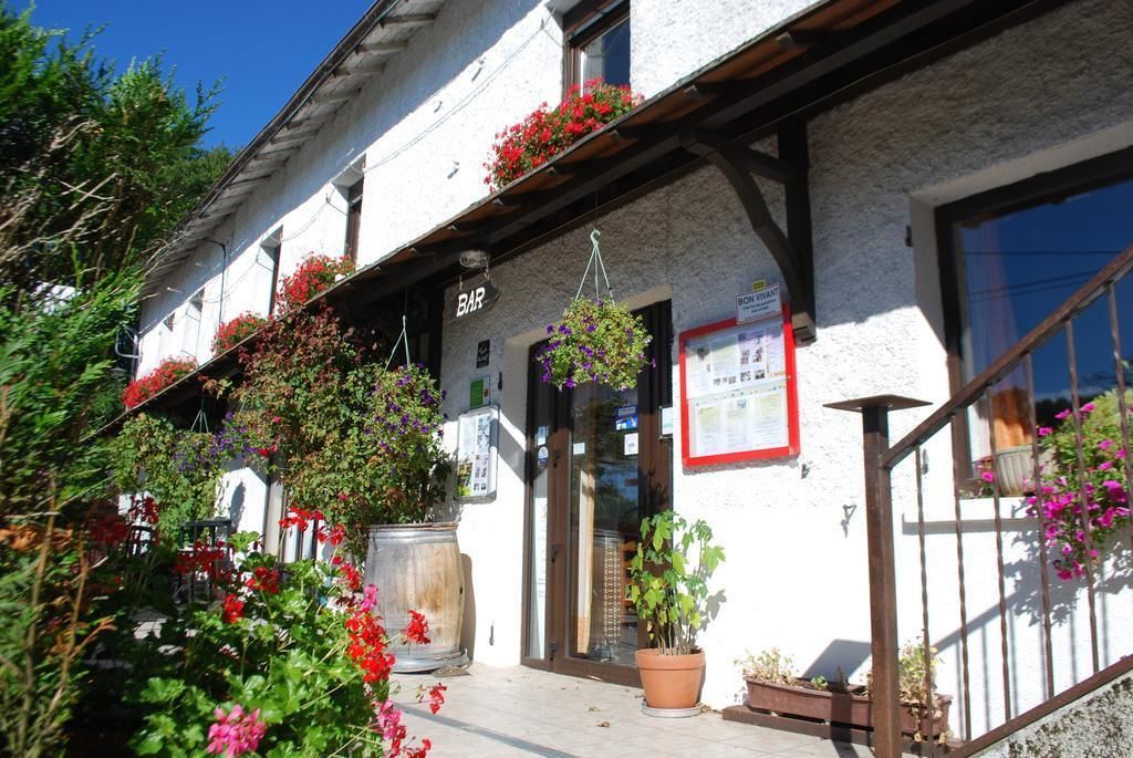 A building with a bar sign, outdoor seating with potted plants, and a wooden staircase.