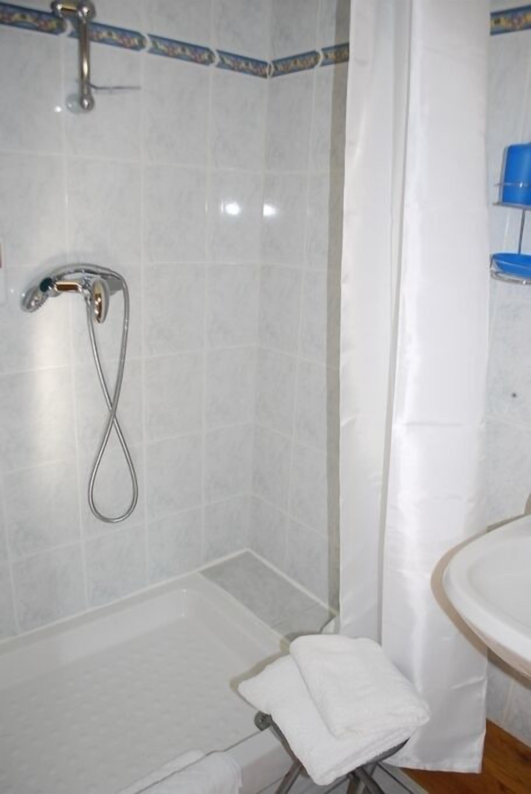 A bathroom with a shower, a sink, and a towel rack.