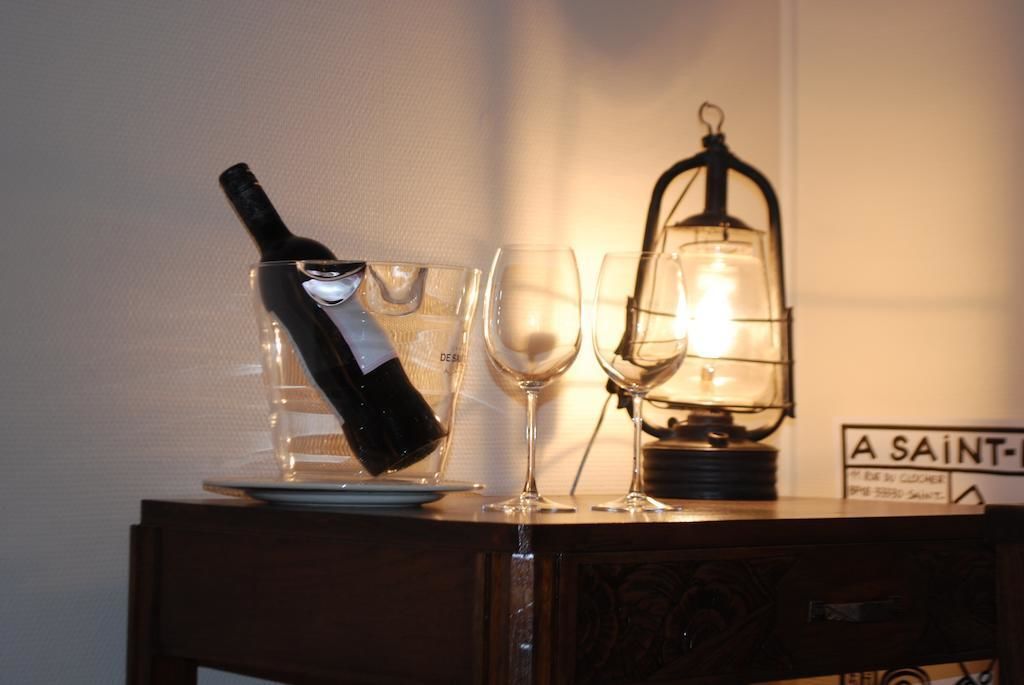 A bottle of wine, two wine glasses, and a lit lantern on a wooden table.