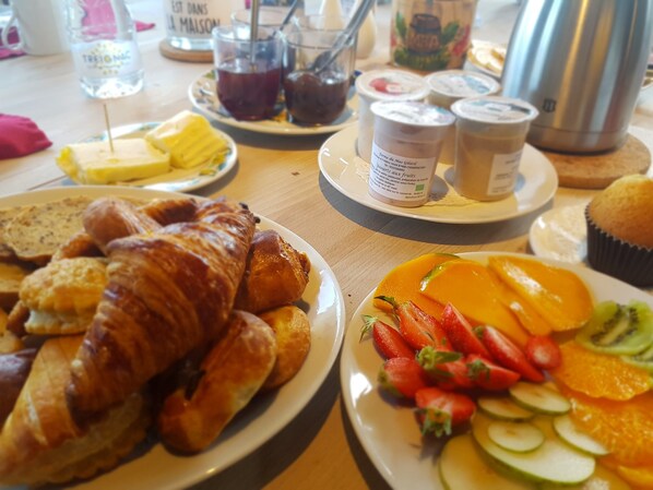 A breakfast table with croissants, fruit, and condiments. - Le Ranch des Lacs, Hôtel Restaurant à Augne (Augne)