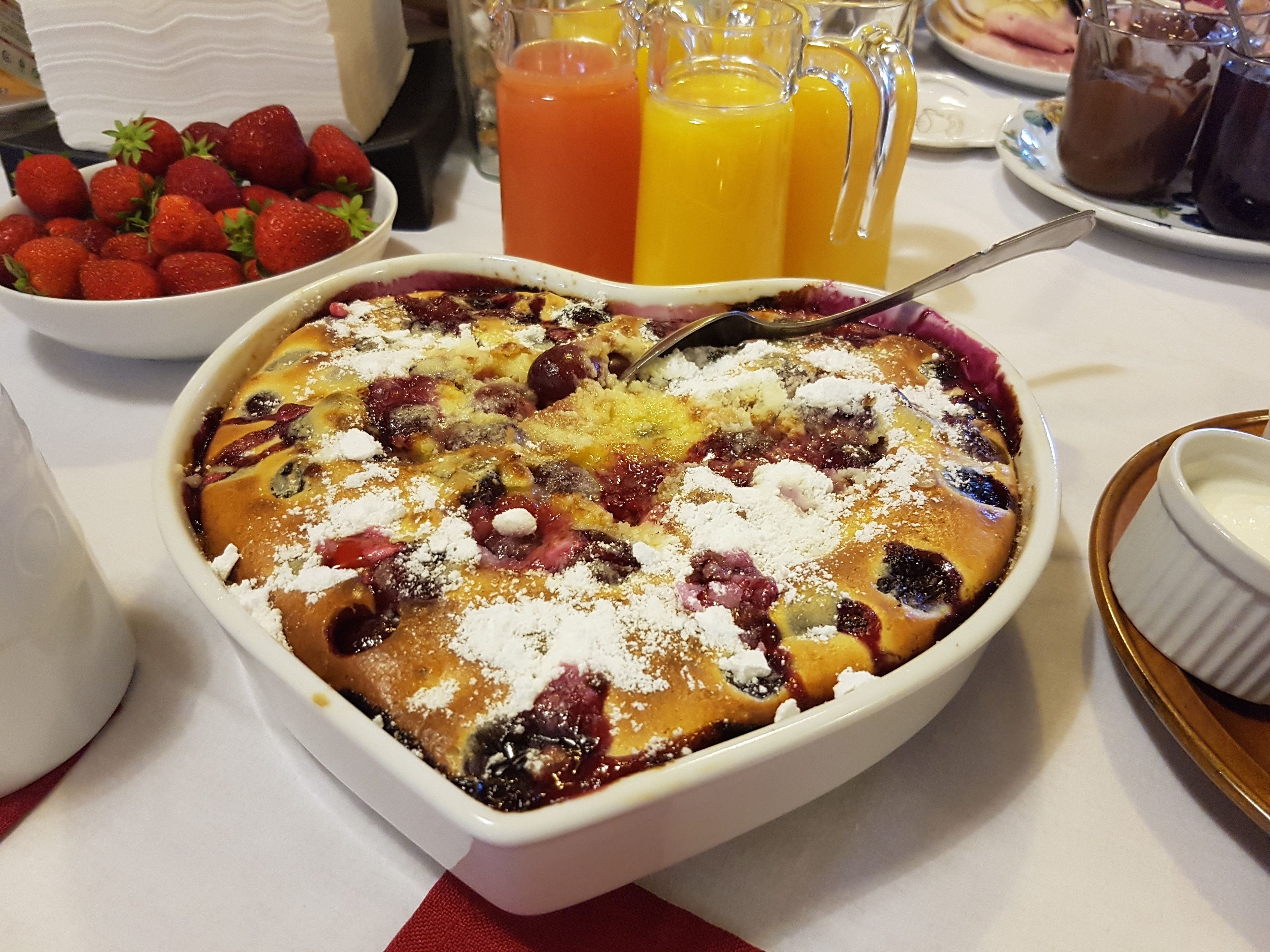 Un dessert composé de fruits rouges et de sucre glace, servi avec un bol de fraises et des carafes de jus d’orange.