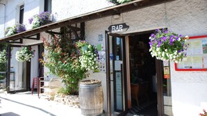 A rustic bar with hanging flower baskets and a wooden barrel outside. - Le Ranch des Lacs, Hôtel Restaurant à Augne (Augne)