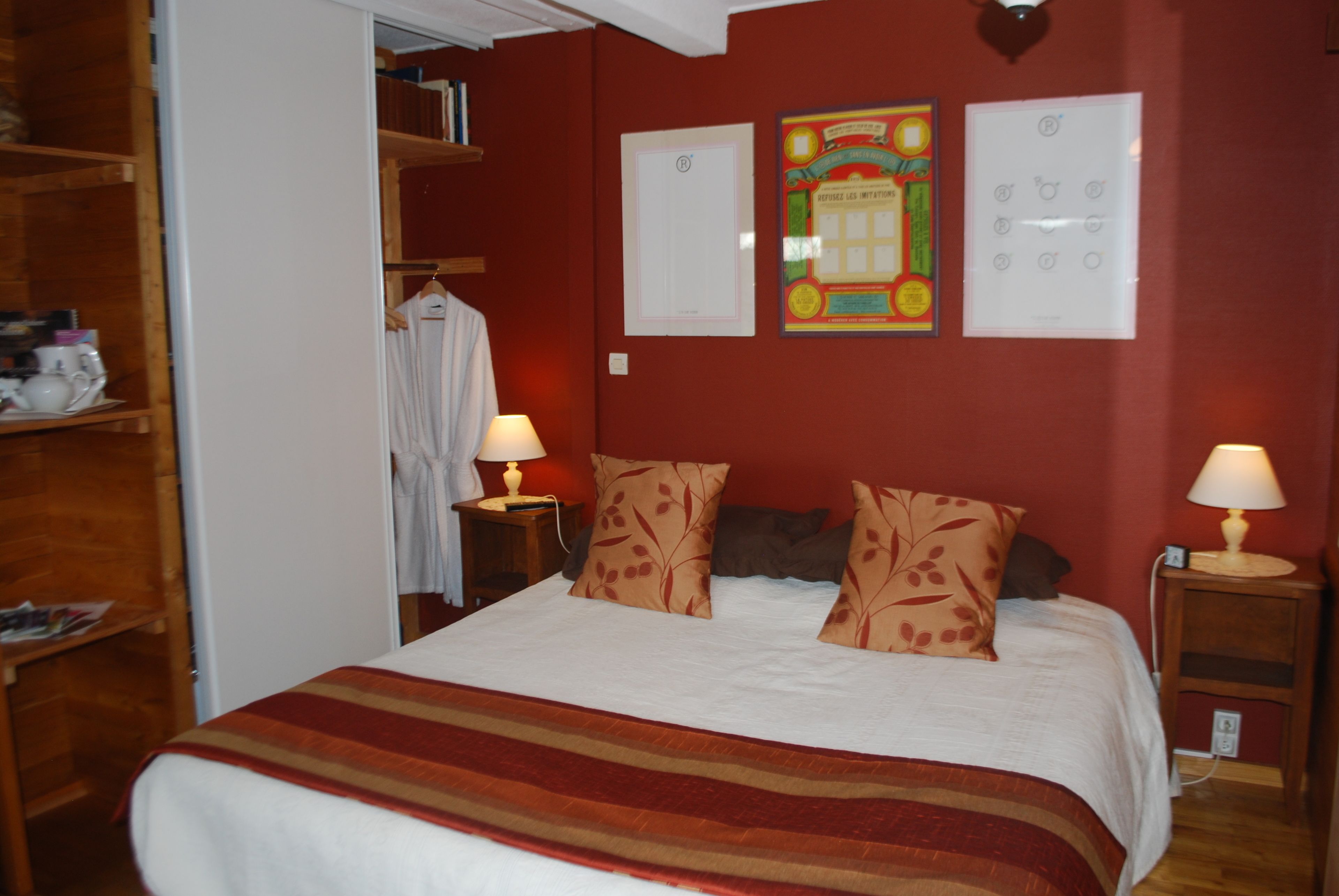 Un dormitorio con cama, dos lámparas de noche, un armario y una puerta que da a otra habitación.