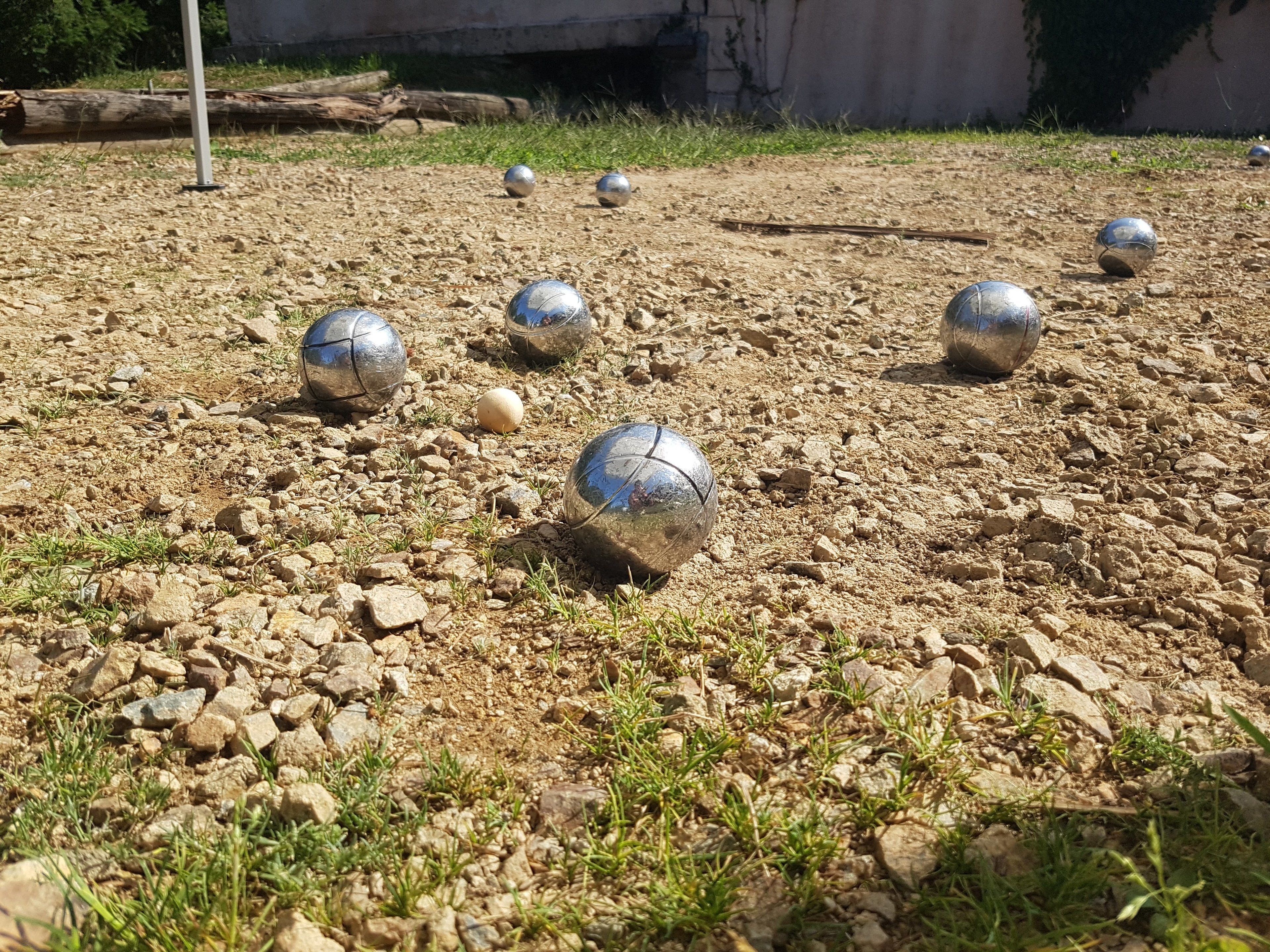A gravel surface with several metallic balls scattered across it.