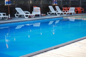 Una piscina amb gandules blanques i taronja alineades al voltant de la vora.