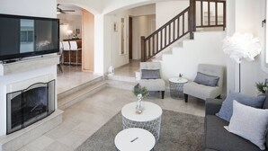 Una sala de estar moderna con chimenea, una escalera y un comedor.