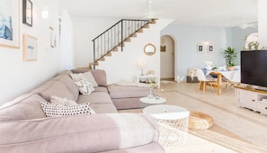 Una sala de estar con sofá, mesa de centro y mueble para televisor.