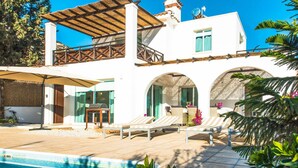 Una villa moderna con piscina, area relax esterna e patio coperto.