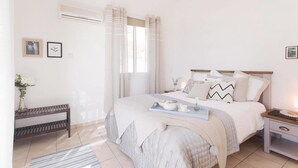 Una camera da letto ordinata con un letto, comodini, una panca e una finestra con tende.