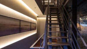 Un interior moderno con una escalera, paredes iluminadas y vistas a un paisaje nevado a través de una ventana.