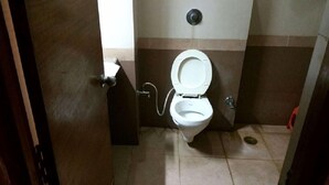 A small, private bathroom with a toilet, a shower, and a towel rack.