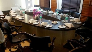 A conference room with a long table, chairs, water bottles, and a vase with purple flowers.