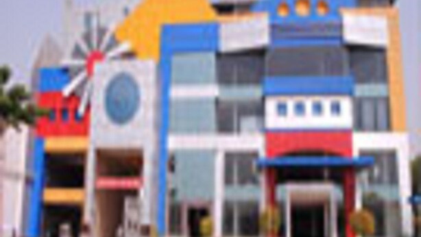 A multi-story building with a prominent windmill, a blue and yellow facade, and a central entrance with a red and white design.