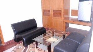 A living room with a sofa, a glass coffee table, and a wooden cabinet.
