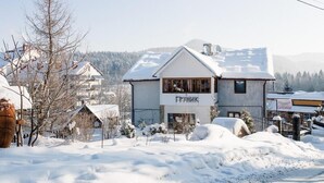 A two-story building with a sign reading "ГРАНИЦИ" in Cyrillic, surrounded by snow-covered ground and trees. - Grunyk Guest House (Yaremche)