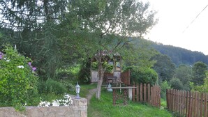 A rustic wooden structure with a stone wall and a wooden fence. - Grunyk Guest House (Yaremche)