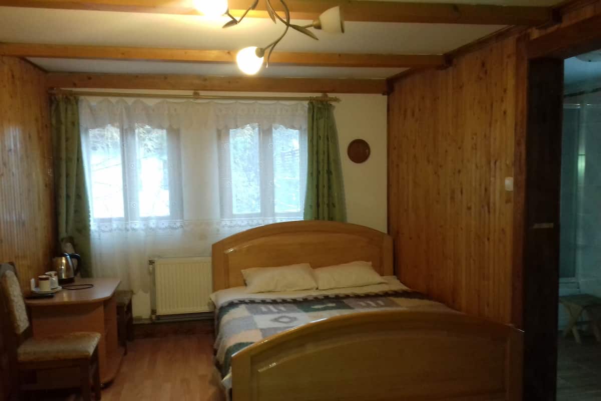 A wooden-framed bedroom with a bed, a desk, and a chair.