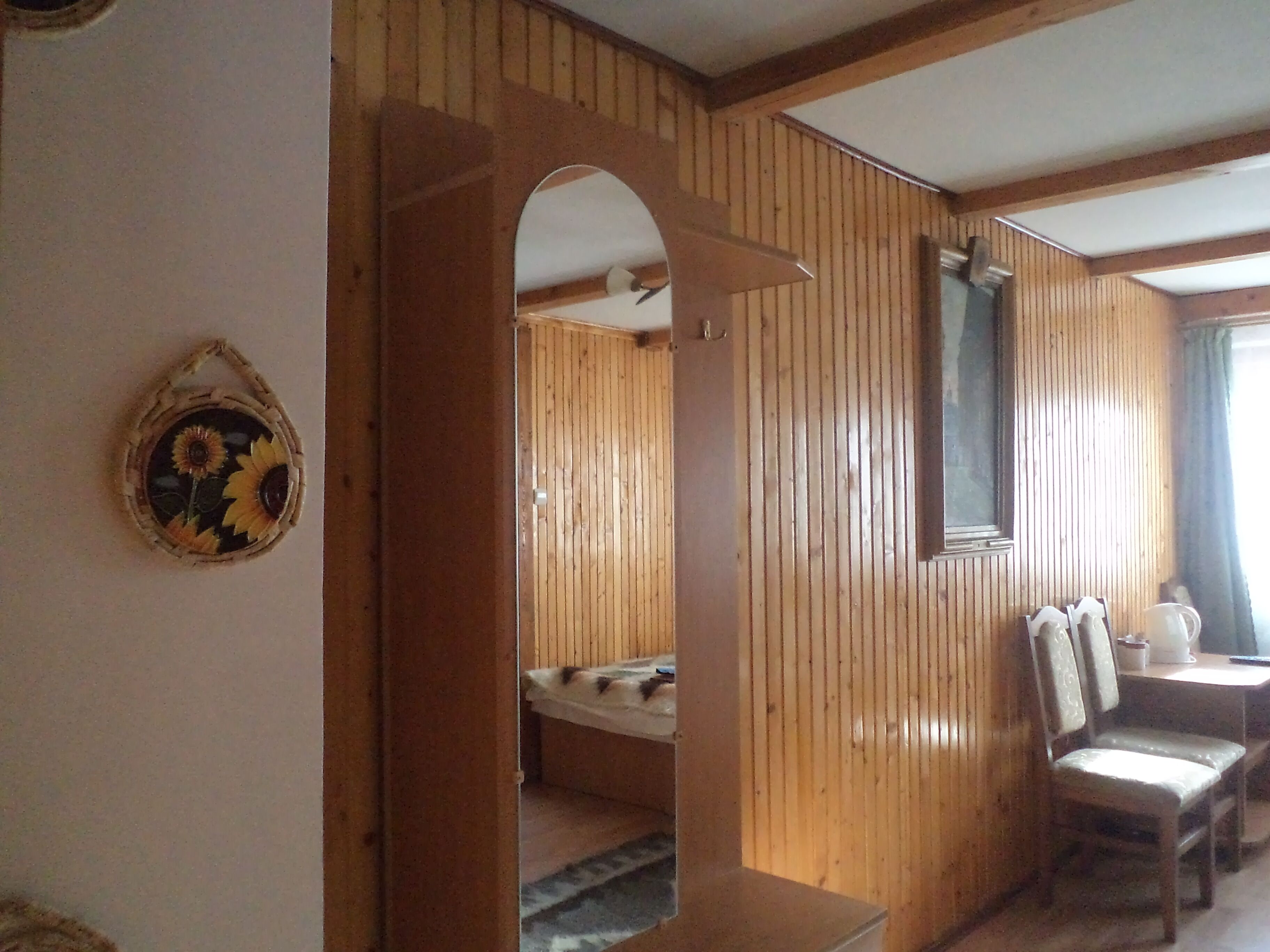 A wooden interior with a bed, a chair, and a small table.